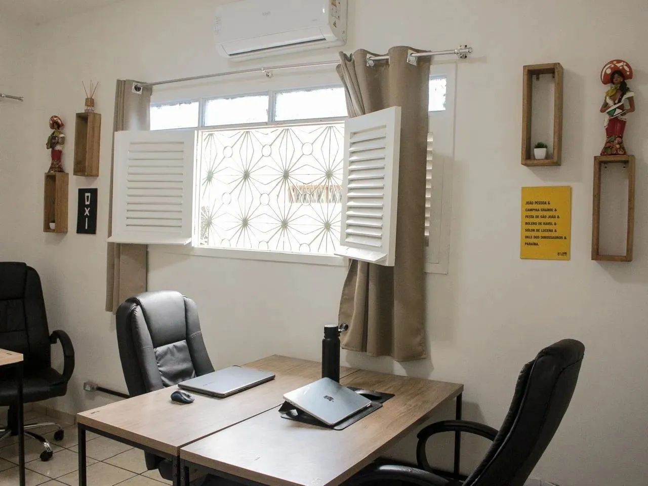 Sala de coworking do LumeHostel com mesas, cadeiras ergonômicas e notebooks junto à janela
